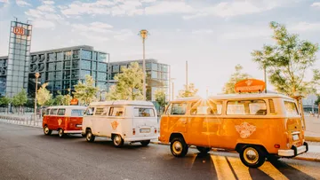 Bunte VW-Busse parken an einer Straßenkante in der Stadt.