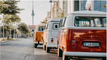 Vier Oldtimer-Vans stehen auf einer sonnigen Straße in Berlin.