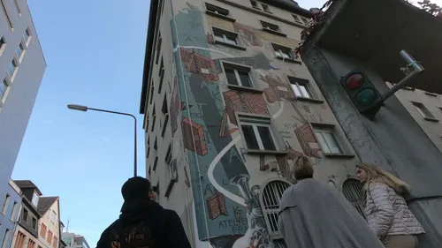 Die Leute schauen sich ein Gebäude mit Wandgemälde und Ampel an.