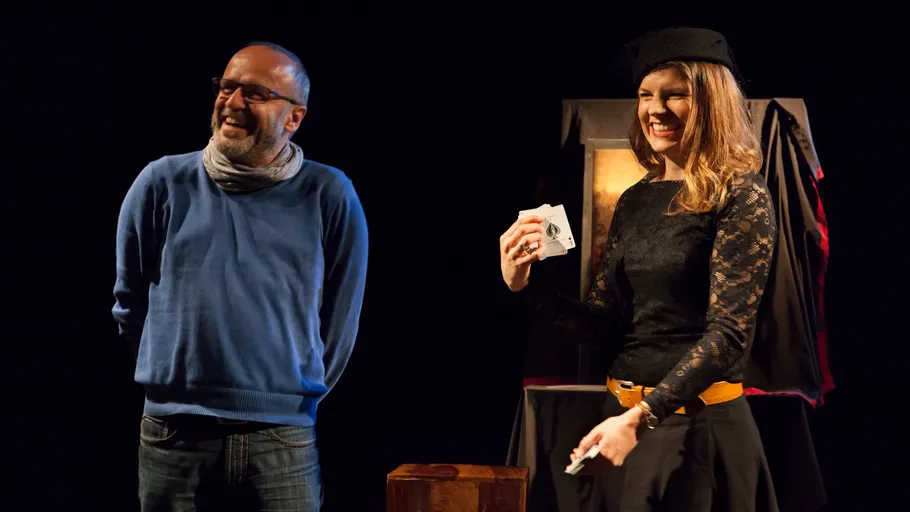 Two people laugh while standing on stage.