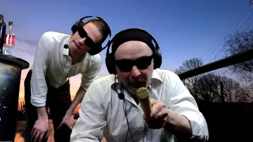 Two men wearing sunglasses pose before sunset.