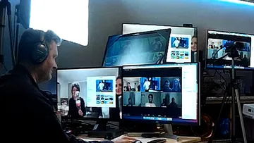 Man works on several screens during a video conference.