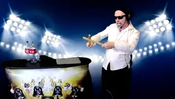 A man plays drums in an illuminated room.