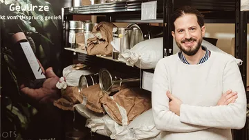 Person standing smiling in front of shelves with spices.