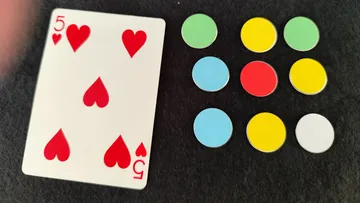 The playing card and coloured chips lie on a black background.