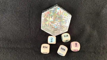 Hexagonal box surrounded by numbered cubes on fabric.