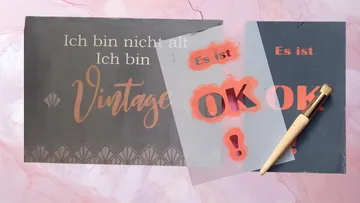 Zwei dekorative Schilder liegen auf einem Tisch.