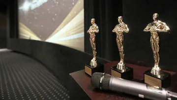 Goldene Statuen stehen neben Mikrofon auf einer Bühne.