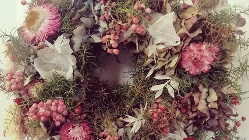 Blumenkranz hängt dekorativ, umgeben von Trockenblumen.