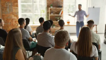 Group listens to a presentation in a modern, bright room.