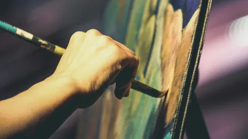 Hand paint on a canvas in a dimly lit room.