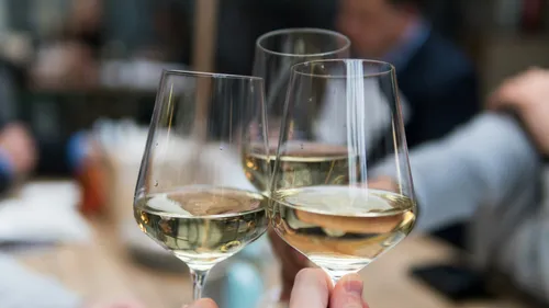 Gläser mit Weißwein stoßen in geselliger Runde an.