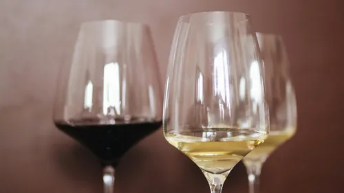 Drei Weingläser stehen, gefüllt mit Rot- und Weißwein.