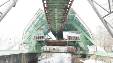 Grüne Brücke über einen ruhigen Wasserlauf im Winter.