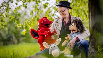 Puppeteer interacts with handmade outdoor dolls.