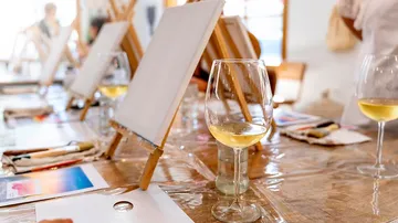 Blank canvases stand on tables while wine is being drunk.