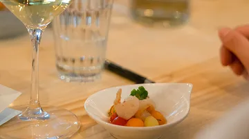 White wine glass is placed next to a small bowl of seafood.