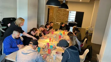 Gruppe malt an einem Tisch in einem modernen Raum.
