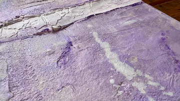 Textured purple surface with cracks and streaks.