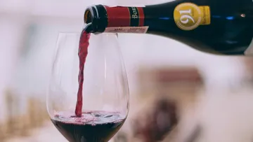 Red wine is poured from a bottle into a glass.
