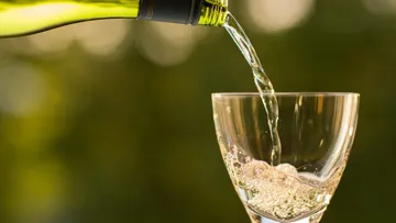 A glass is filled with water from a bottle.