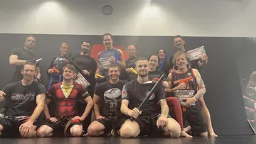 Group of fighters pose with exercise equipment in a gym.