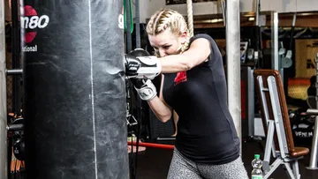 A female boxer punches a sandbag in the gym.
