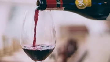 Red wine is poured from a bottle into a glass.