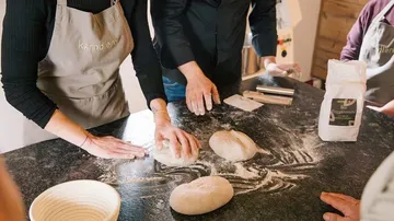 Dough is worked on a worktop by several people.
