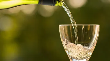 Eine Flasche gießt sprudelndes Wasser in ein Glas.