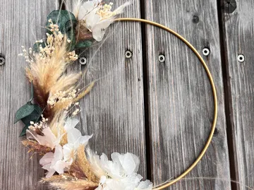Golden ring decorated with dried flowers on wood