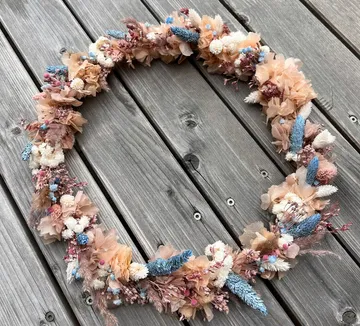 A blooming wreath is lying on a wooden background.
