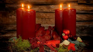 Rote Kerzen brennen auf einem festlichen Adventskranz.