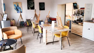 Leerer Kunstraum mit Tischen und Staffeleien.