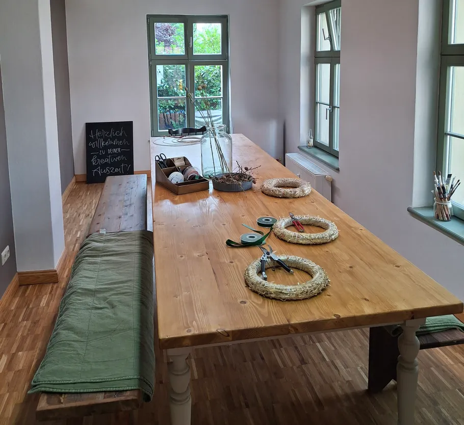 Wooden table with craft materials in a bright room.