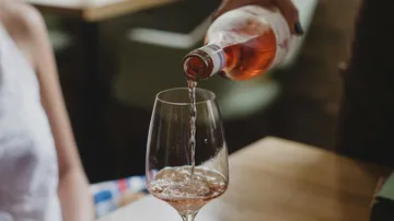 A glass is filled with rosé wine in a restaurant.