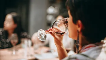 Frau trinkt Wein in geselliger Runde.