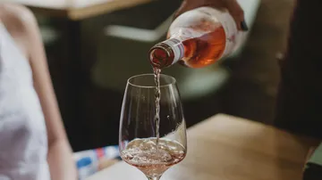 Ein Glas wird mit roséwein gefüllt, in einem Restaurant.