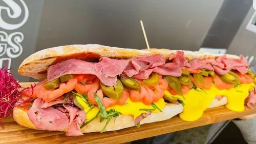 A sandwich with sauce, ham and chilies.