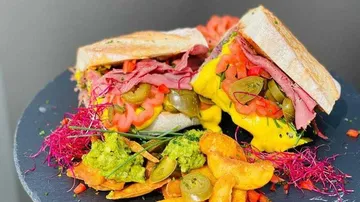 Sandwiches mit Fleisch, Gemüse und Chips auf schwarzem Teller.