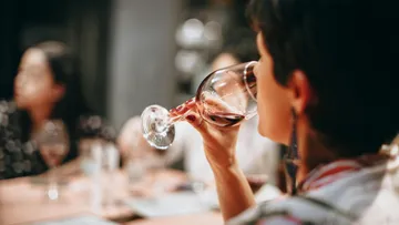 A glass of red wine is held in a relaxed atmosphere.