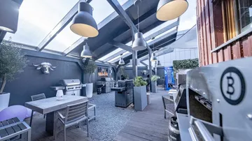 Cosy outdoor area with barbecue and dining area under roof.
