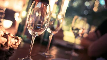 Wine glasses are placed on a table in warm light.
