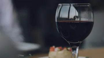 Red wine in a glass is next to a dish.