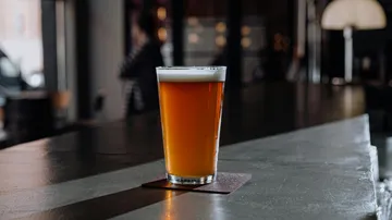 A glass of beer is on a bar counter.