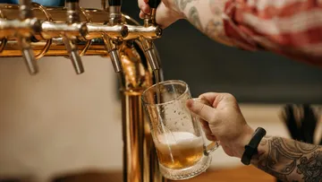 Glas wird mit Bier an einem Zapfhahn gefüllt.