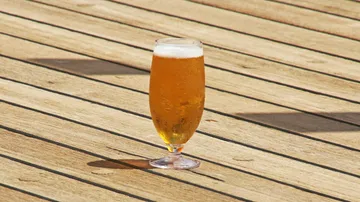 Ein Glas Bier steht auf einem Holzdeck.