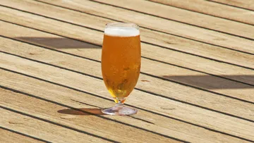 A glass of beer is on a wooden deck.
