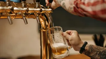 Beer glass is filled with beer at a gas pump.