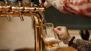 Glas wird am Zapfhahn mit Bier gefüllt in Bar.